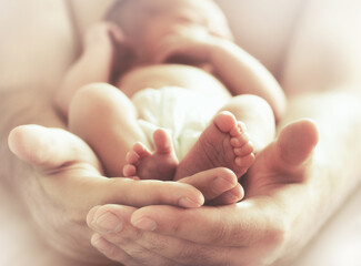 Sleeping newborn baby on male hands