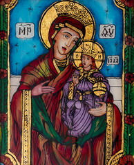 Icon painted on reverse glass in the naive orthodox style of Eastern Europe depicting Virgin Mary and baby Jesus.
