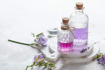 Obraz na płótnie Canvas Violet flower lavender scented perfume liquids in retro bottles with a vintage white background, selective focus
