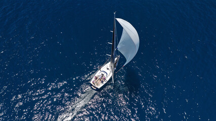 Aerial drone top down photo of beautiful sail boat with trained crew cruising in deep blue Aegean...