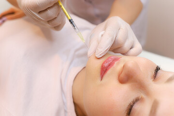 The cosmetologist performs the chin lift procedure by injecting beauty injections
