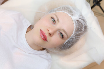 Fototapeta na wymiar a beautiful girl lies after cosmetic procedures to increase the lips with hyaluronic acid