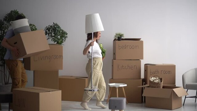 Happy married couple takes out the packed things from the apartment and dancing. Moving to a new home, minimalism and decluttering concept