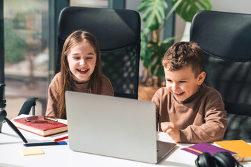 Smiling boy and girl study online in home at the laptop