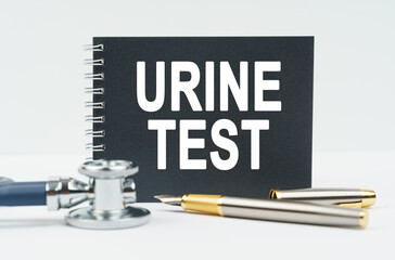 On a white background lies a stethoscope, a pen and a black notebook with the inscription - URINE TEST