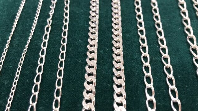Different caliber silver chains perspective flat lay green background . Mobile FullHD footage