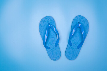 Blue rubber flip-flops isolated over blue background, pair of thongs, shot above