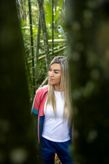 Vertical shot of a Hispanic woman with blonde hair posing on a forest background