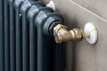 a fragment of a blue gray colored heating radiator against the background of anthracite gray tiles