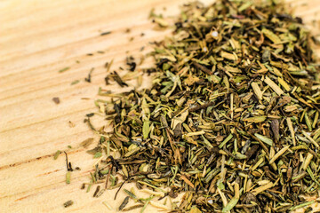 Dried thyme spilled on brown wooden board