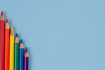 Colored pencils with rainbow colors of LGBT gay pride flag arranged on light blue background. Top view