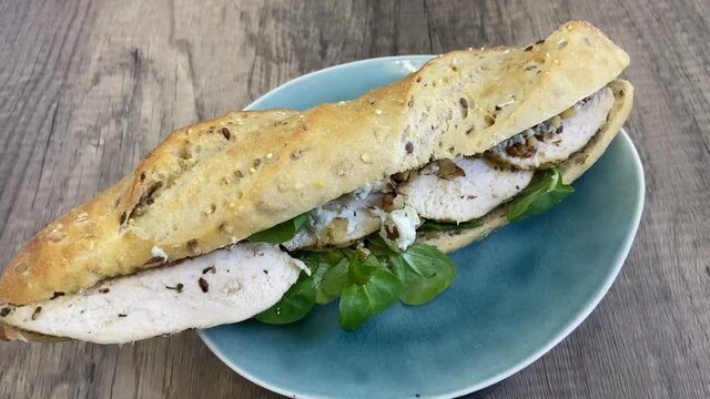 Sandwich baguette au poulet, noix et fromage sur une assiette