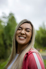 Vertical shot of a Hispanic woman with blonde hair smiling on a blurred background