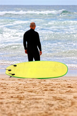  Un surfeur et sa planche face à l'océan