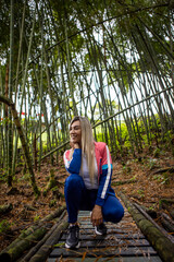 Vertical shot of a Hispanic woman with blonde hair posing on a forest background