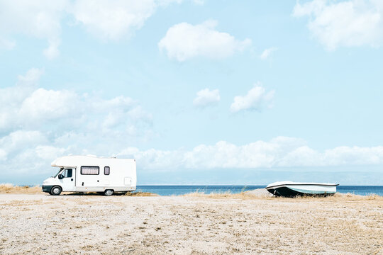 White camper van parked near the sea on the beach. Tourist season on the mediterranean sea. Sicily. Ionian sea.