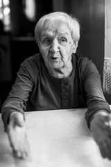 An old woman talks by gesturing her hands. Black and white portrait.