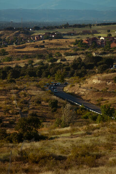 Carretera en el campo verde y amarillo, varios coches pasando en una curva.