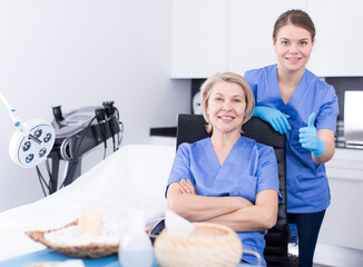 Two satisfied beauticians posing in clinic of esthetic medicine .