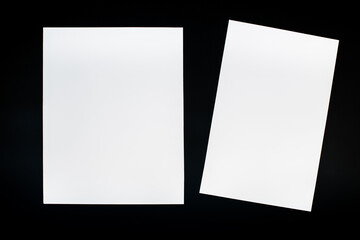 A white sheet of A4 paper on a black background. A4 sheet of paper cut in half