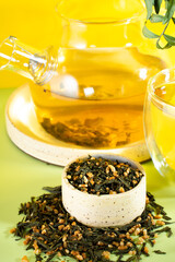 Japanese green tea Genmaicha.Tea leaves with fried brown rice on a bright yellow background with a shadow.Slimming trend tea concept. a cup of tea. brew a transparent teapot