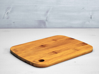 Cutting wooden board on light gray painted wood surface and gray background.