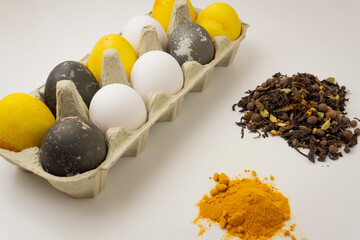 Easter eggs painted with natural dyes. Eggs colored with turmeric and hibiscus lie with uncolored...
