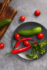 Fresh vegetables on a black plate. Parsley cucumbers, peppers and tomatoes close up.