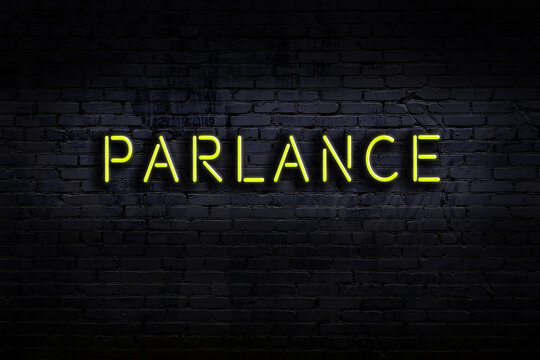 Night view of neon sign on brick wall with inscription parlance