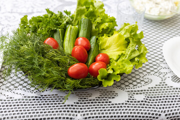Close up view of plate with green lettuce and vegetables on white table cloth background. 