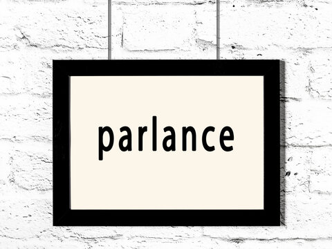 Black frame hanging on white brick wall with inscription parlance