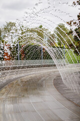 Water splashes from a fountain in a summer park. 