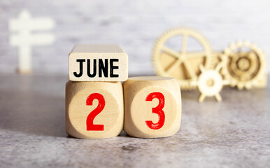 Calendar reminder event concept. Wooden cubes with numbers and month on June 23 with sunlight.