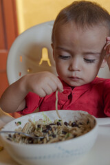 portrait of little boy eating at the table with his own hands