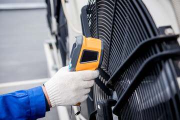 Technician uses a thermal imaging infrared thermometer to check the condensing unit heat exchanger.