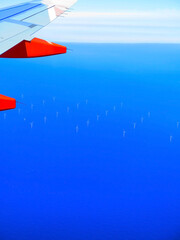 Airplane flying over the sea, windmills in the sea near the Netherlands. Aerial view from the plane. Plane wing. Aerial view at wind park. offshore windmill park.