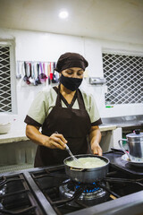 Vertical shot of a Hispanic woman making a dish in the kitchen