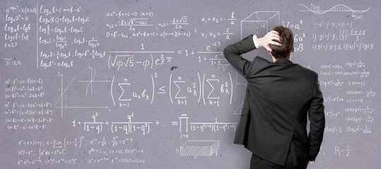 Self-education concept with back view on man in black suit in front of college blackboard with...