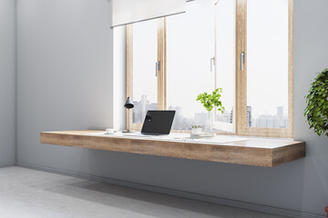 Bright grey room with a wooden desk and computer closeup, big window and concrete floor, interior design and workspace concept, 3d rendering, mock up