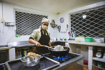 Vertical shot of a Hispanic woman cooking chicken with mushroom sauce