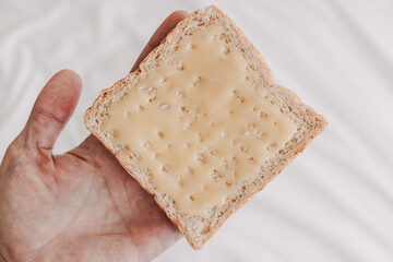 Hand holding bread with sweetened condensed milk on top. Easy dessert.