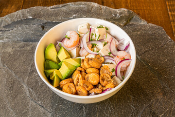 white bowl of fish and prawn ceviche with huge fried corn kernels