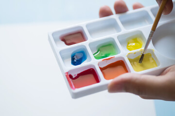 Hand holding brush and mixing watercolor palette prepare for painting