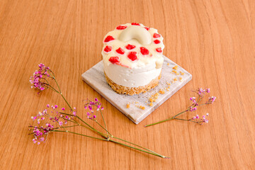 Mini cheesecake with white chocolate and raspberry on top, biscuit soil, flowers and placed
