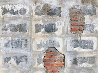 Broken concrete block wall hole was repaired by brick and cement into hole wall. Easy and rare masonry work style of house or building wall.