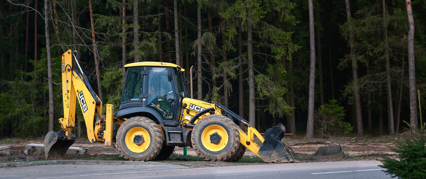 Minsk, Belarus. Apr 2021. Tractor JCB 4CX parked on construction site in the forest. Yellow JCB tractor, excavator - heavy duty equipment vehicle.