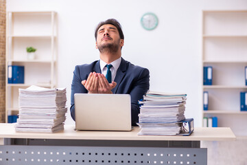 Young businessman employee and too much work in the office