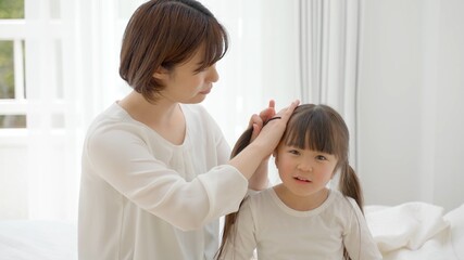 女の子の髪を結ぶ女性