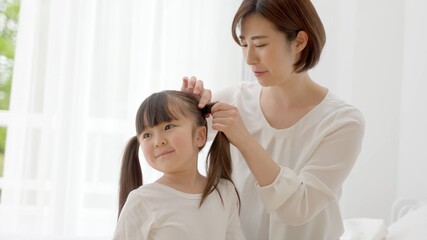 女の子の髪を結ぶ女性