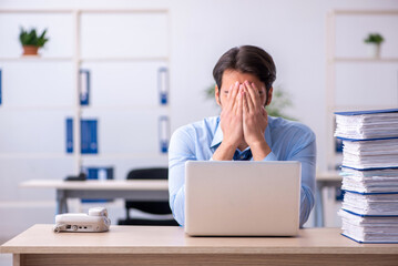 Young male employee and too much work in the office